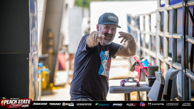 Bombshell RC Racing team owner Matthew Martin smiles and points toward the camera beside the pit area at the 2026 Georgia Peach State Classic. A candid moment from the race weekend’s Good Times photo gallery.